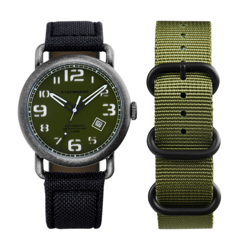 Stalingrad Rodim Watch with a sandwich dial. Green dial with white hands and numbers, Silver case and a black cordura strap with a green nato strap next to it front view of watch on white background.